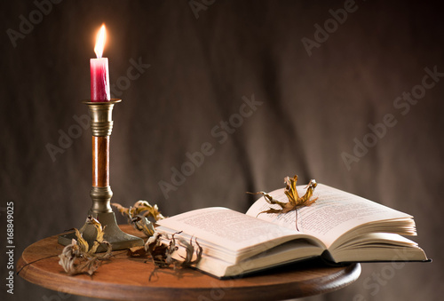 An open book. Lighted candle.
