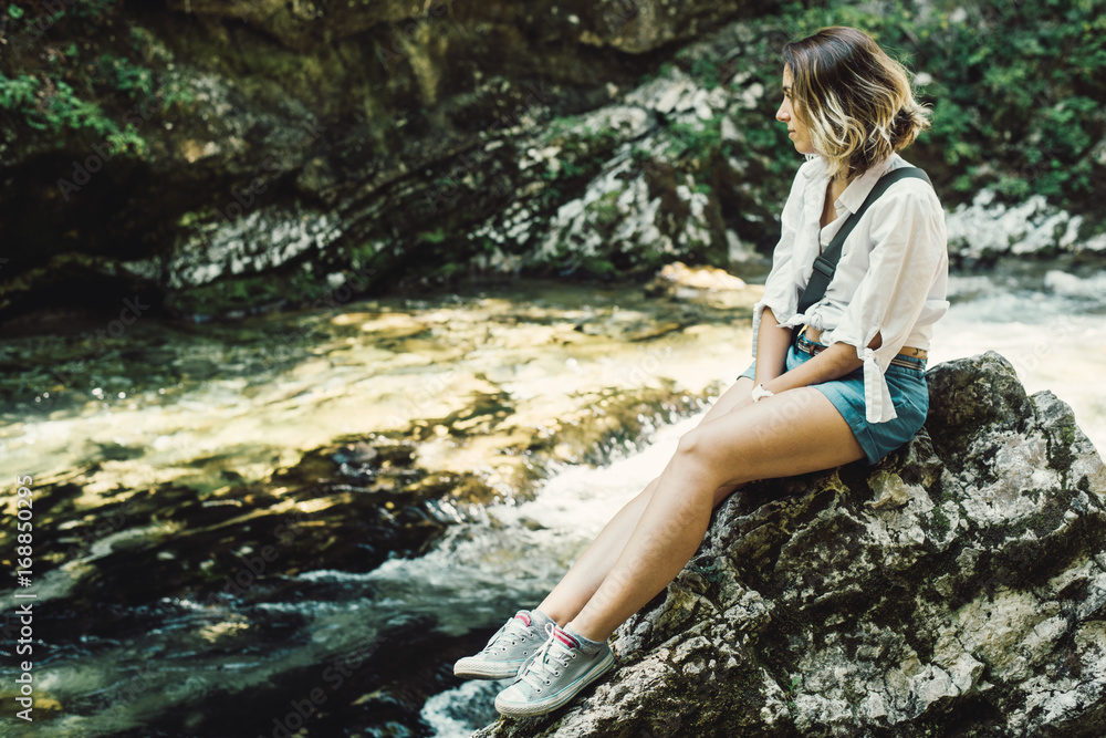 Caucasian girl enjoys in nature/sitting by creek