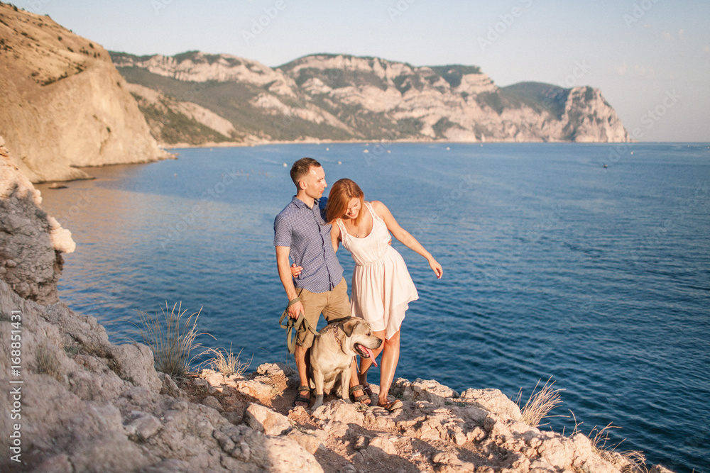 Couple in love walking near sea with a dog