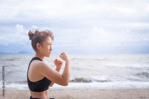 Sporty asian women fitness age 30-40 are warm up muscular body for jogging at the beach in sunrise light . Moments of joy and relaxation in the morning. Customise pastel bright colors tone .