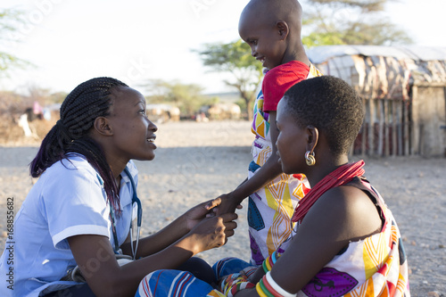 Nurse examing Mother and Daughter in rural village. Kenya, Africa. photo