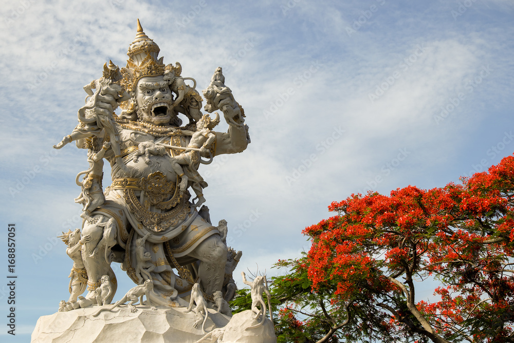 monkey king statue with red flowers at Uluwatu temple, Bali