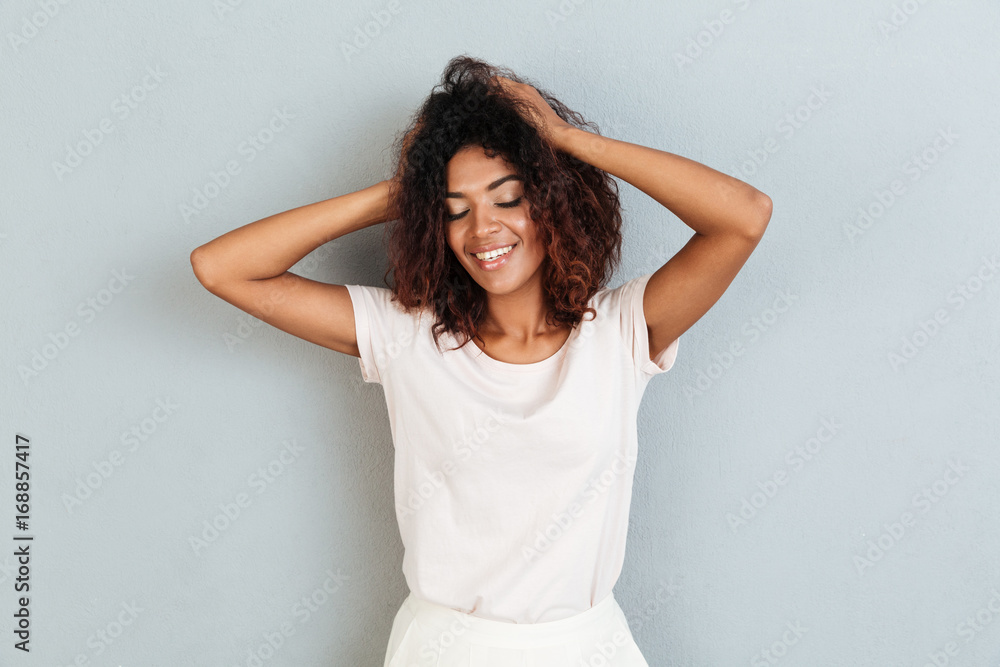 Smiling young african woman standing over grey wall. Smiling young african woman standing over grey wall.