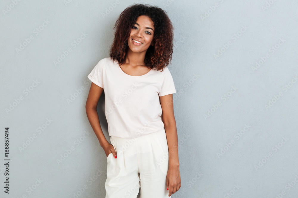 Pretty young african woman standing over grey wall. Pretty young african woman standing over grey wall.