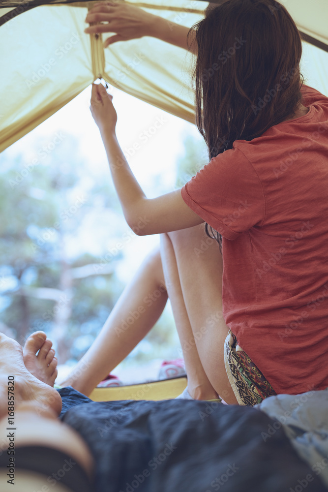 view from inside a tent at the forest and woman emerge from tent. travel and hiking concept, Tourist tent inside with people