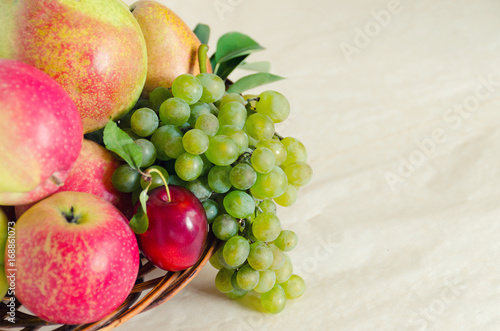 Ripe fresh fruit in a wooden plate on a light background. The concept of harvest. View from above. Copy space