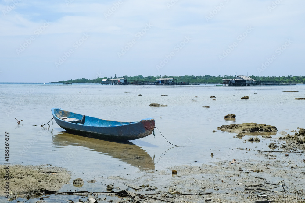 blue drift boat close to an indoensian tropical fisher village blue drift boat close to an indoensian tropical fisher village