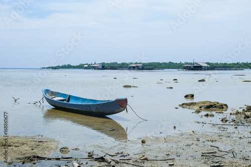 blue drift boat close to an indoensian tropical fisher village photo