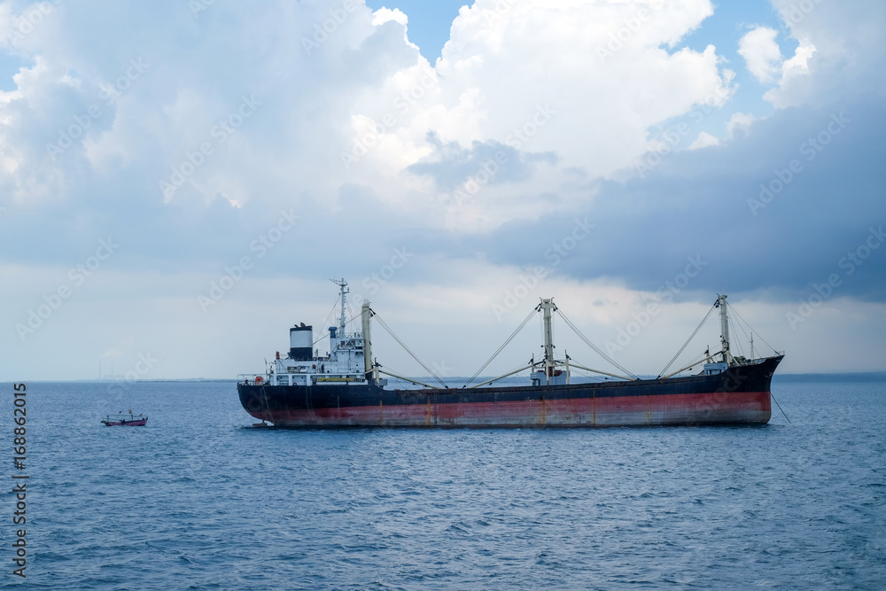 cargo ship and a small boat on the tropical java sea close to Jepara