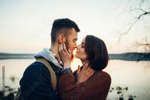 man and woman standing with canoe and paddle on coast of lake in sunny morning