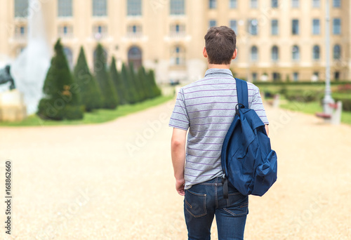 Young student walking to the university. Back view