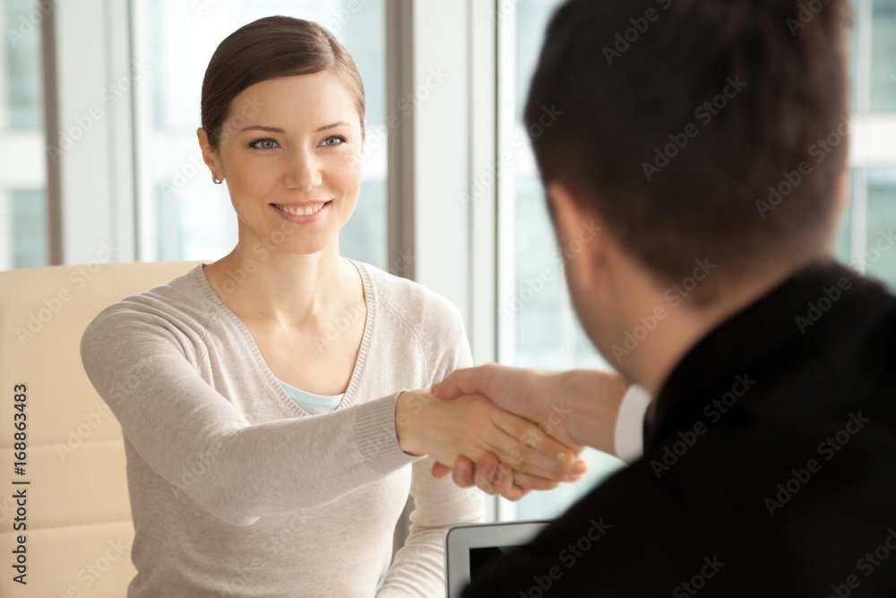 Smiling beautiful woman shaking male hand, greeting handshake of female applicant arriving at job interview, businesswoman making good first impression at meeting with new partner, women in business