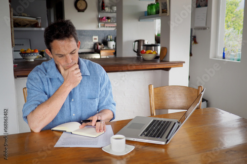 Man reading a document in his home office.