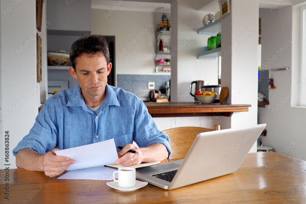 Man in home office reading a document Man in home office reading a document