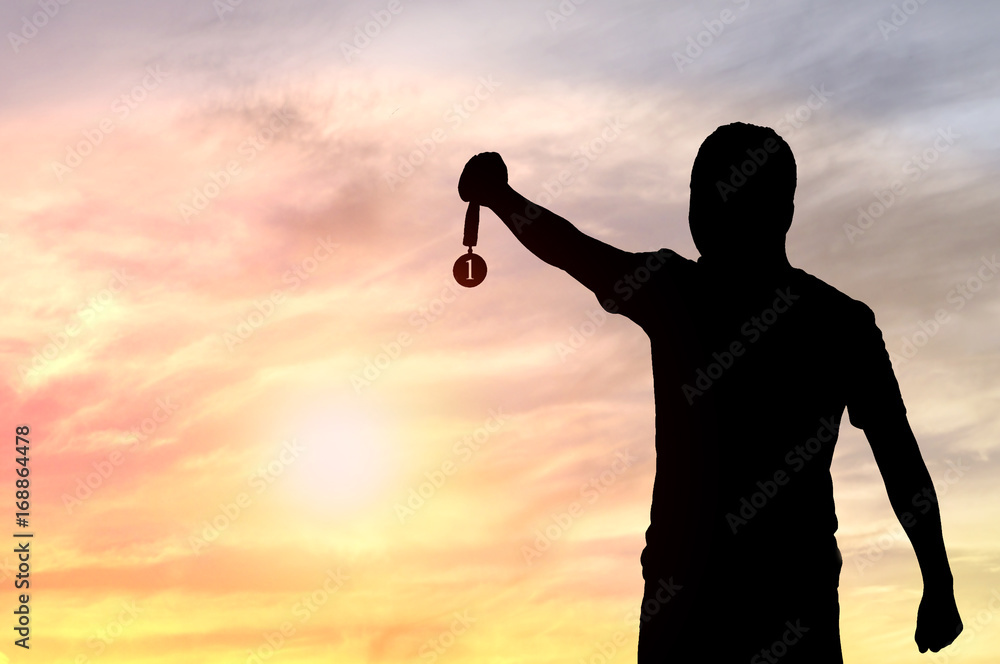 Silhouette of man holding Golden Medal on sunset background, concept as winner and champion in sport and business