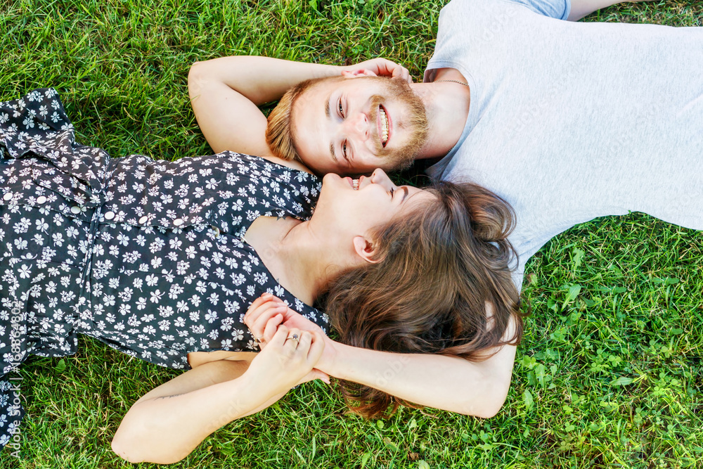 The beautiful couple lie on the green grass and smiling. The beautiful couple lie on the green grass and smiling.