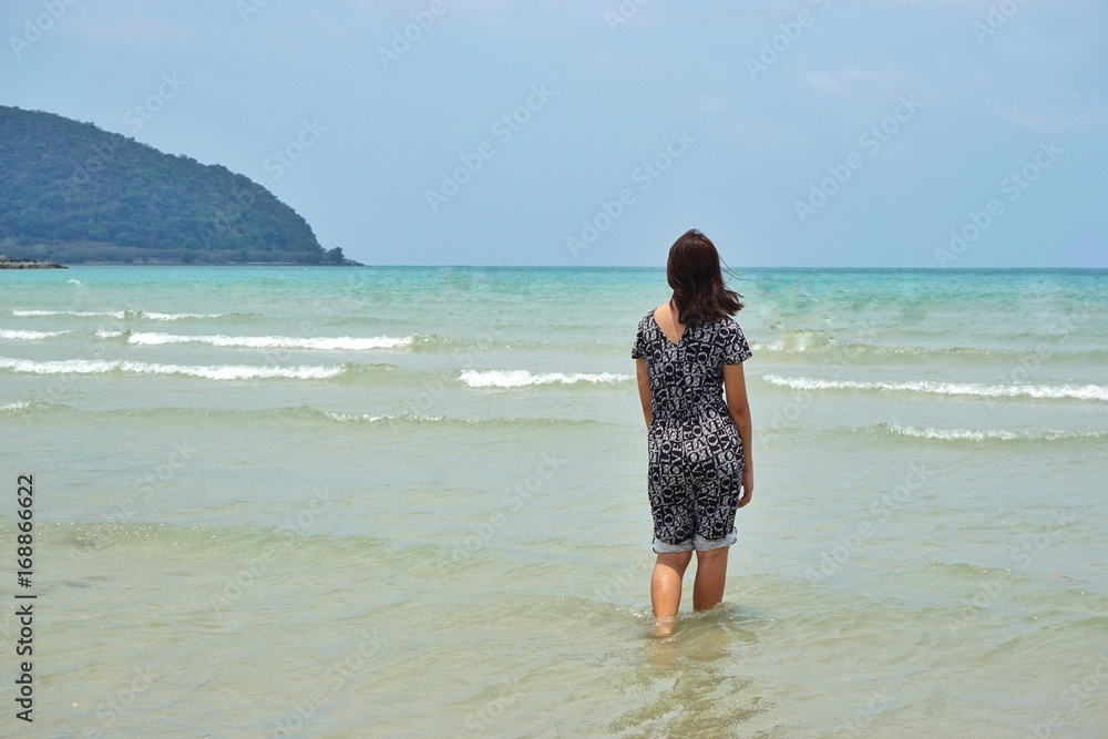 Beautiful Asian woman is standing in the sea. Picture with copy space.
