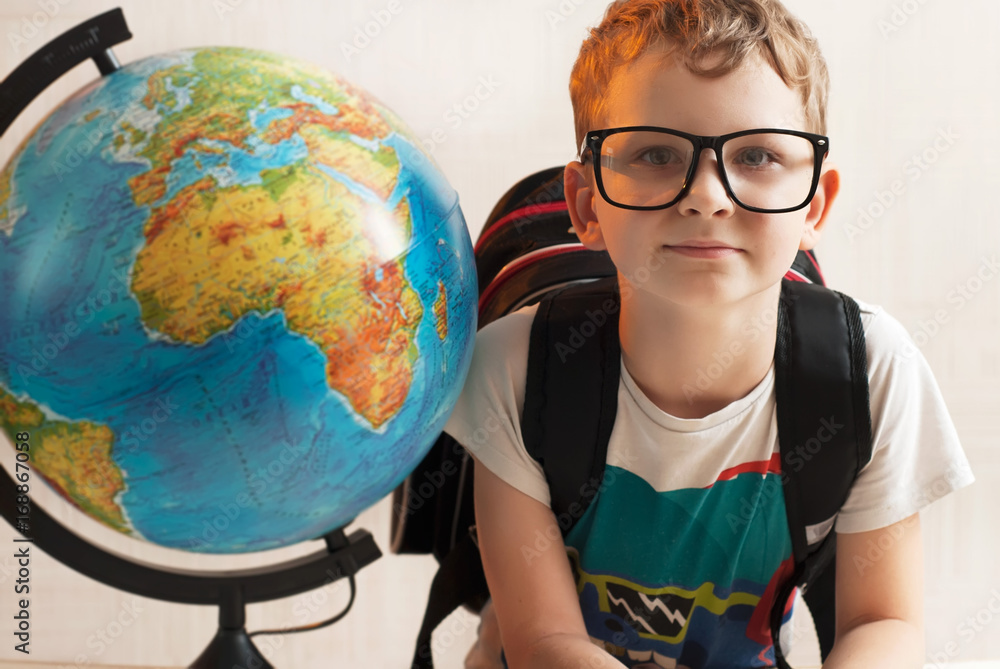 Portrait of little boy with glasses, holding a globe. The nerd with the globe