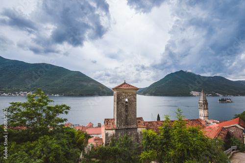 Famous ancient Perast village on Kotor bay in Montenegro. Panoramic view to Perast Old Town tiled roofs  clouds and mountains of Boka Kotorska marina.