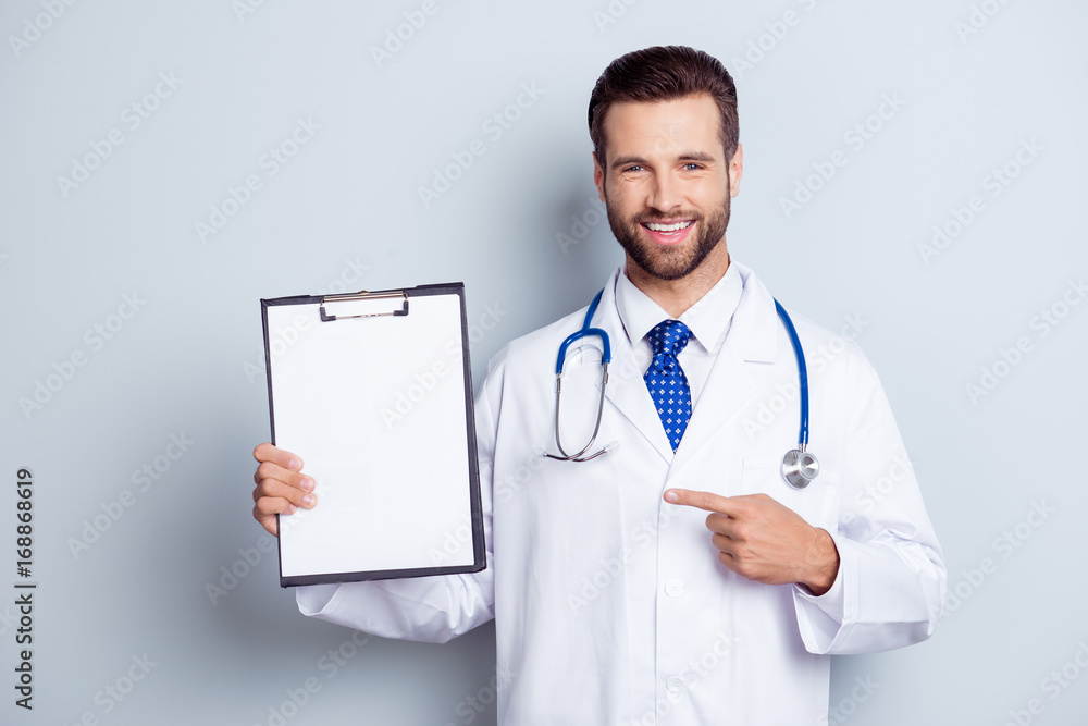 Cheerful handsome bearded smiling intern is holding the clipboard. Doc is wearing white uniform and a tie, stands on a light white background Cheerful handsome bearded smiling intern is holding the clipboard. Doc is wearing white uniform and a tie, stands on a light white background