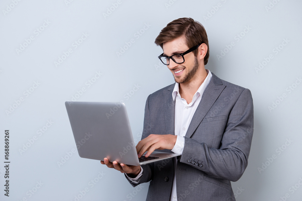 Young handsome smiling manager in suit holding laptop and chatting with his business colleagues Young handsome smiling manager in suit holding laptop and chatting with his business colleagues