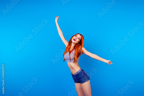 Dream big! Young cute foxy in summer outfit on bright blue background. She is so happy, jumping
