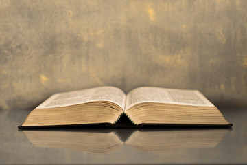 Bible on a glass dark table. Beautiful gold background.Religion concept.
