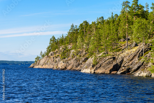 The rocky coast of the island is covered with pine trees. Ladoga lake skerries, Pitkyaranta, Karelia, Russia. photo