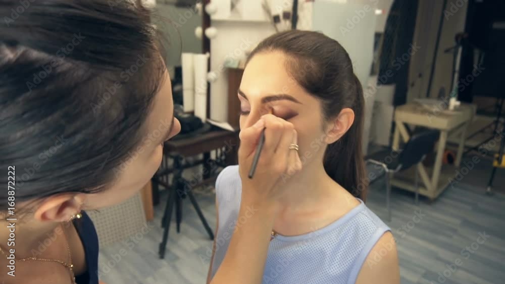 Young beautiful woman applying make-up by make-up artist Young beautiful woman applying make-up by make-up artist