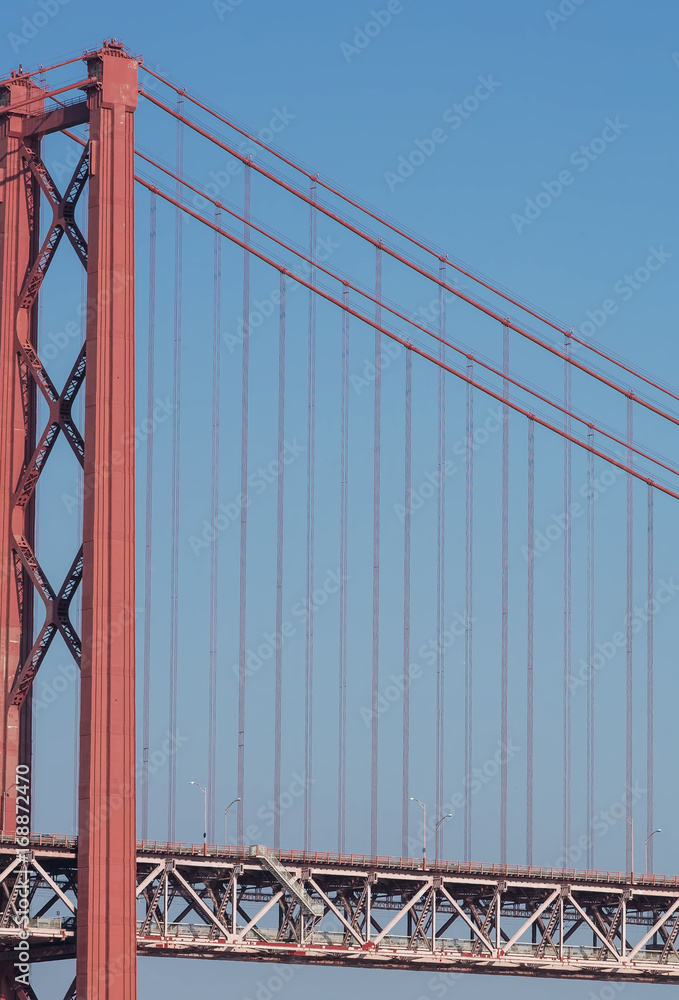 Beautiful view of the red bridge, Ponte 25 de Abril in Lisbon. The bridge connects two cities across the river. Concept of architecture, construction, transportation Beautiful view of the red bridge, Ponte 25 de Abril in Lisbon. The bridge connects two cities across the river. Concept of architecture, construction, transportation