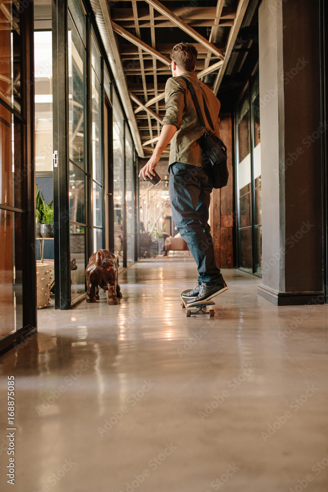 Obraz premium Young man skateboarding in modern office