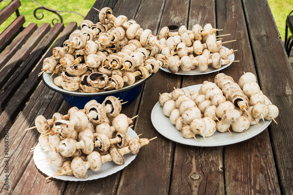 Mushroom skewers on wooden sticks ready for BBQ party on rustic