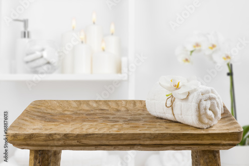 Wooden table with spa towel on blurred bathroom shelf background