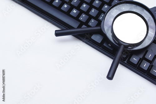 Magnifying Glass And Computer Keyboard Over White Background