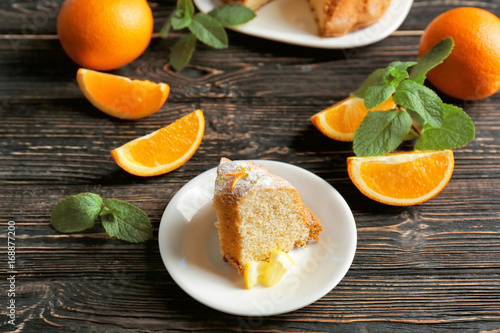 Plate with citrus cake and sliced lemon on wooden table