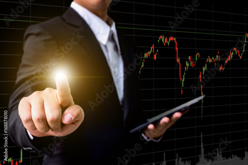 Hand of businessman touching virtual screen with stock market chart background, Business financial or investment trading concept, copy space