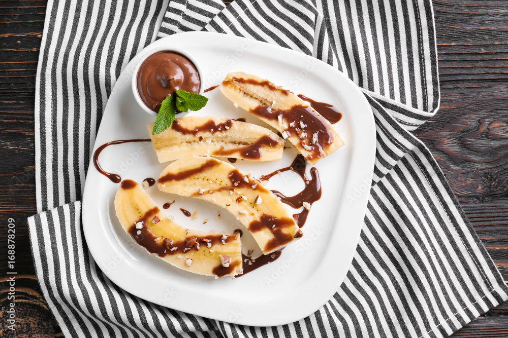 Plate with delicious sliced bananas and chocolate sauce on table Plate with delicious sliced bananas and chocolate sauce on table