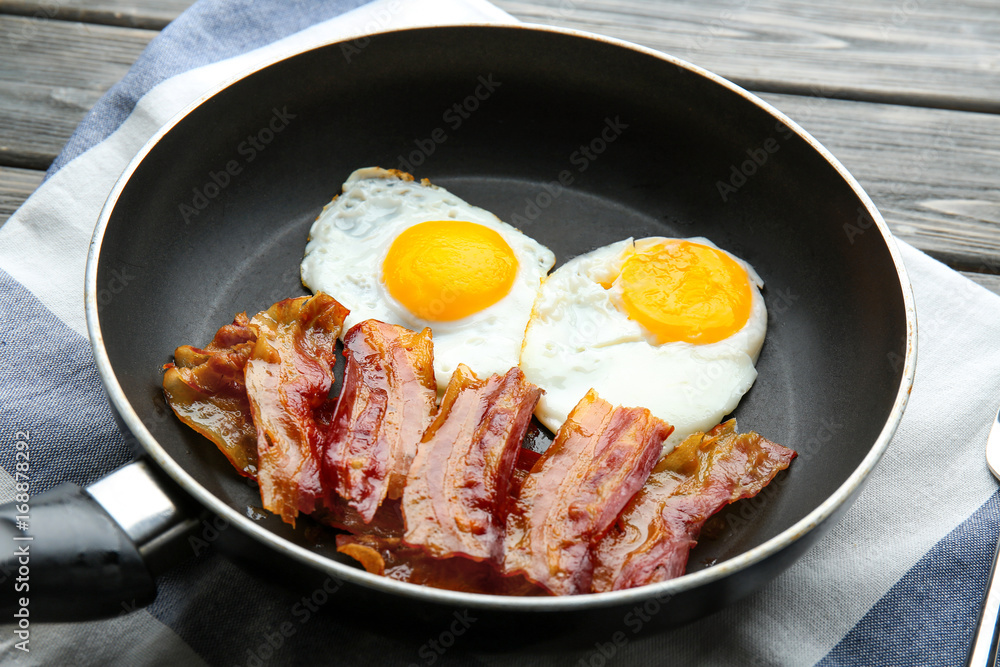 Frying pan with eggs and bacon on table Frying pan with eggs and bacon on table