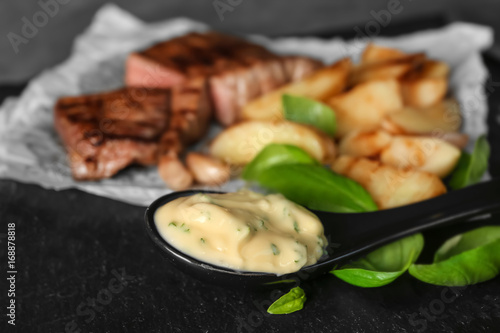 Spoon with delicious sauce for steak on table, closeup