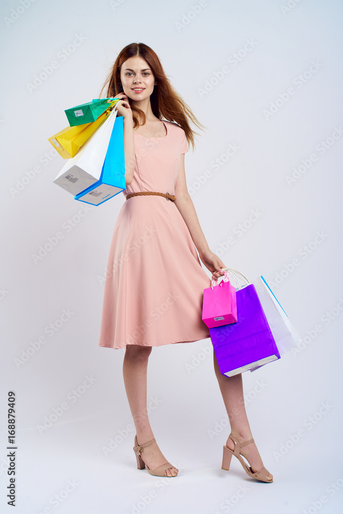Young woman on a light background in a dress holding packages, shopping, full-length