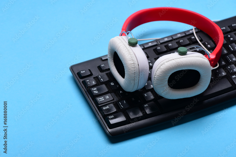 Earphones in red and white color with computer keyboard Earphones in red and white color with computer keyboard