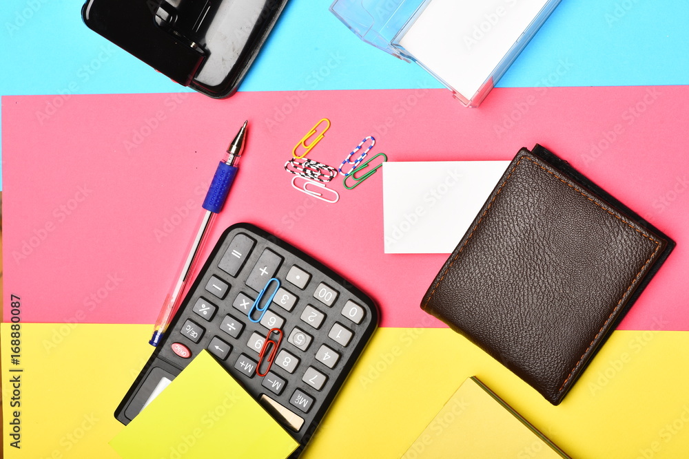 Calculator, hole punch, business card holder on colourful background Calculator, hole punch, business card holder on colourful background