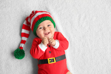 Cute little baby in Santa costume lying on soft fabric