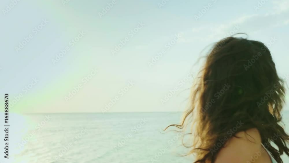Young woman leads behind herself, portrait. Goes along the beach, smiles, hair croaks in the wind. Follow me Young woman leads behind herself, portrait. Goes along the beach, smiles, hair croaks in the wind. Follow me