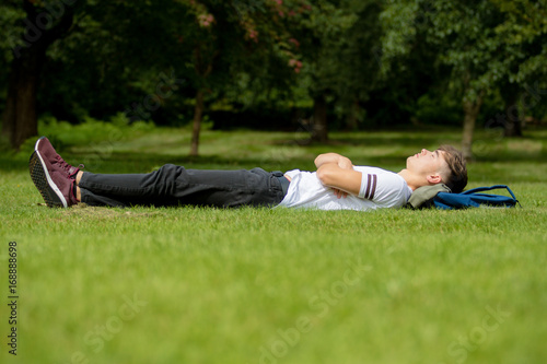 Teenage boy laying on grass on a summers day