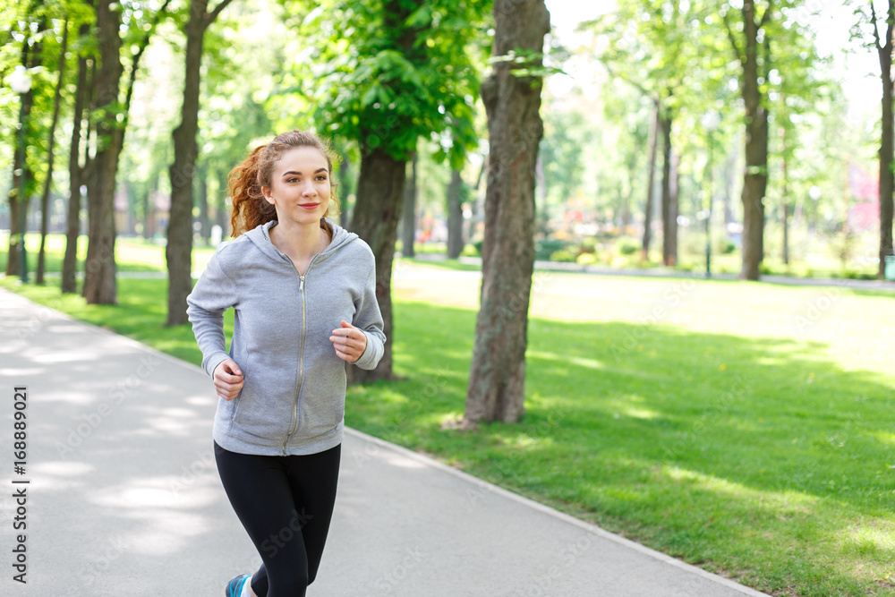 Young woman jogging in green park, copy space Young woman jogging in green park, copy space