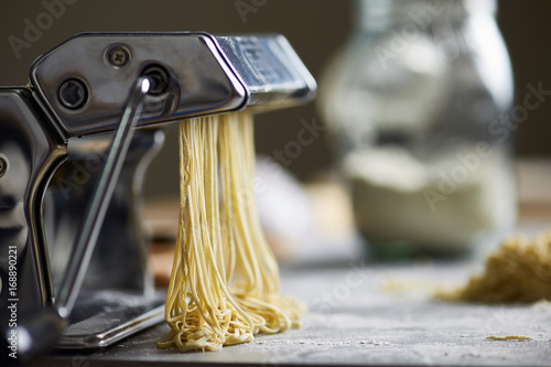 Noodles in machine on floury table.