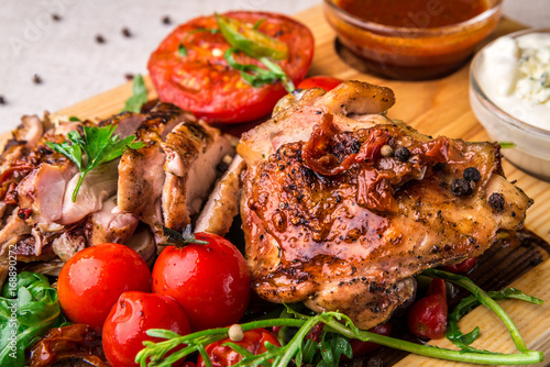 Appetizing fried chicken thighs, decorated with tomatoes and onions. Horizontal frame