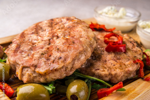 Appetizing fried chicken cutlet, decorated with olives, pepper, with sauce. Horizontal frame