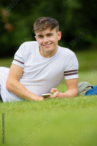 Teenage boy laying on grass on a summers day